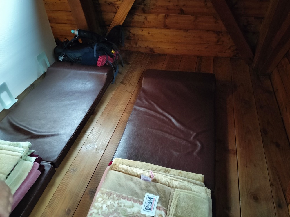 お部屋。マットが敷いてあり、毛布が一人2枚。持参したインナーシーツを使う